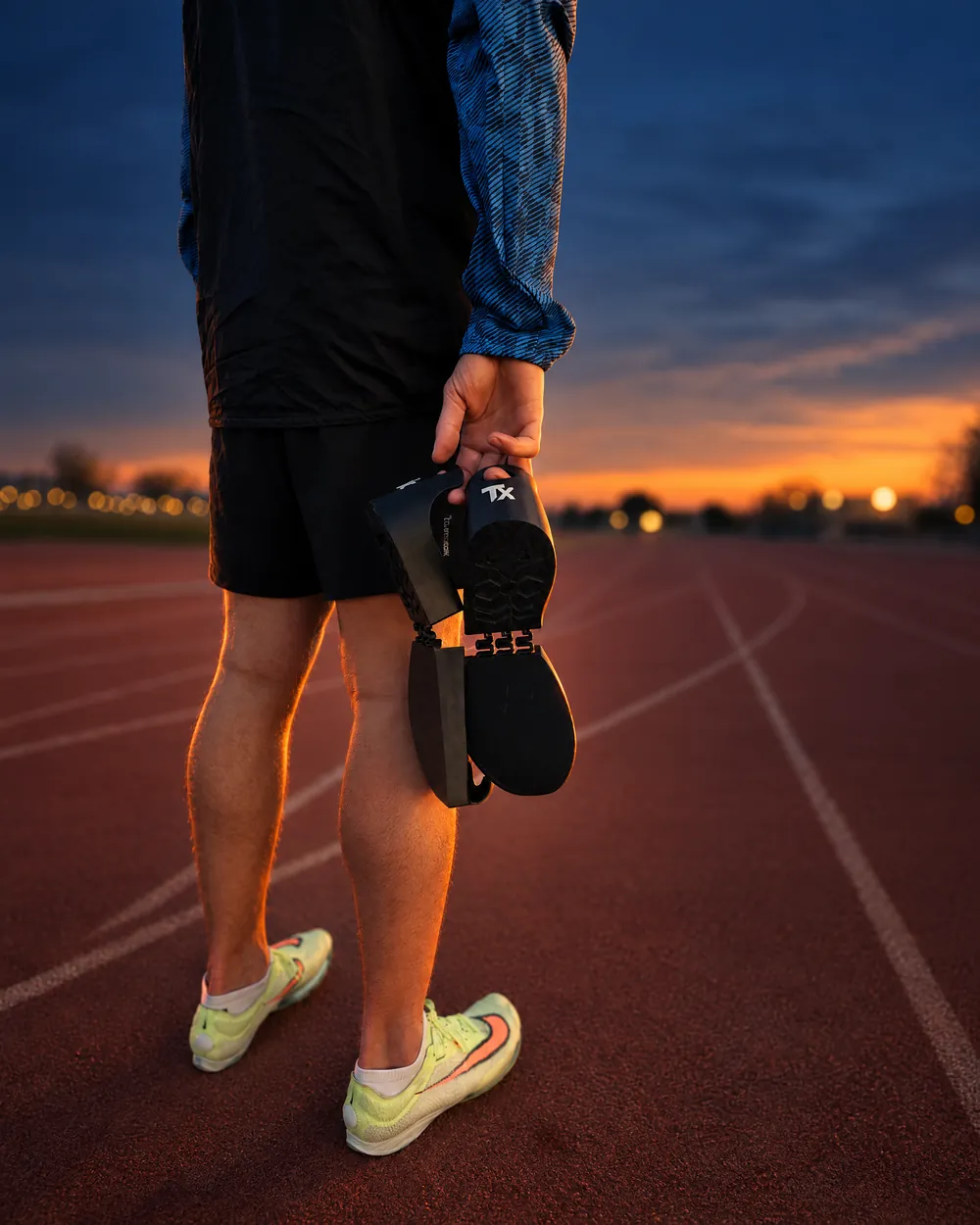 Atleta parado en la pista con sus spikes en la mano, cada uno con el TangoX puesto